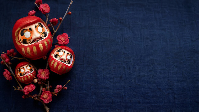 Red daruma dolls with plum blossoms for Japanese New Year wishes