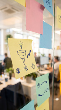 Brainstorming Sticky Notes on Glass Board in Modern Creative Office