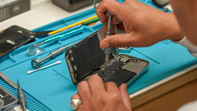Repairing smartphone opened with visible internal components in electronics repair laboratory