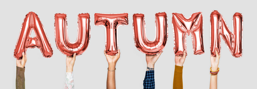 Hands holding balloons spelling Autumn