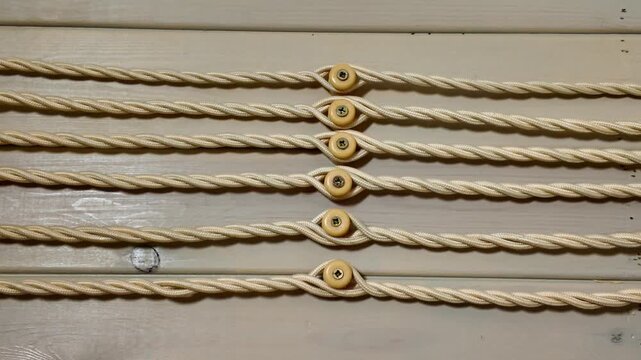 Retro-style fabric-covered electrical wiring running horizontally along a painted wooden wall. Old-fashioned insulators secure the twisted cables