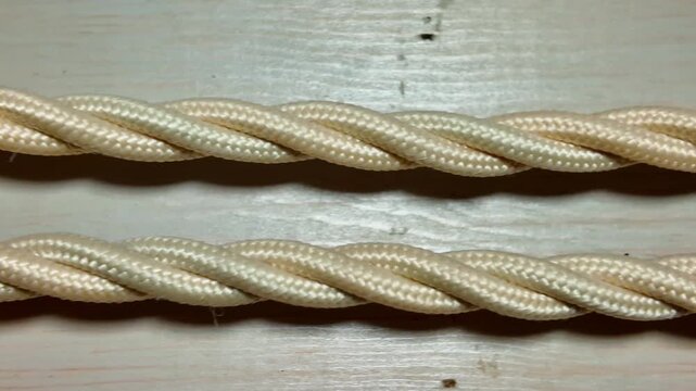 Close-up view of old-fashioned, fabric-covered electrical wires. The braided texture and classic design evoke a sense of nostalgia and craftsmanship