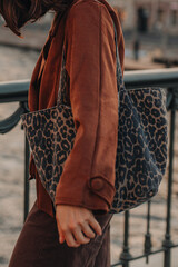 Trendy young woman wearing a brown suede jacket and carrying a leopard print bag, modern street style urban fashion © asauriet