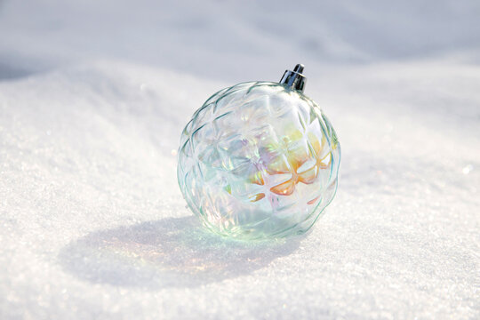 Ornate glass ornament resting on snow during a sunny day in winter season