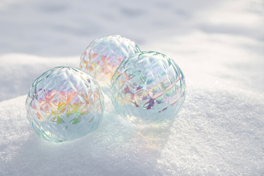 Colorful glass spheres resting on snow during winter
