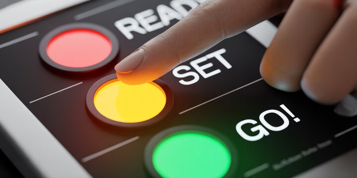Close up of a finger pressing a yellow set button on a black control panel with ready and go