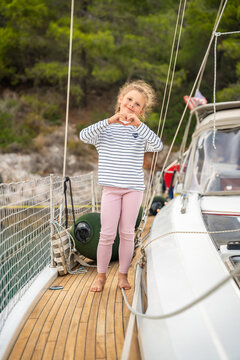 Young girl making heart shape with hands on sailing yacht in Croatia. Happy childhood moment represents love, joy and positive emotions during family vacation