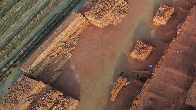 Bangladesh. Aerial pull-up over a brick field, showing fired and raw bricks being processed and stacked throughout the compound.