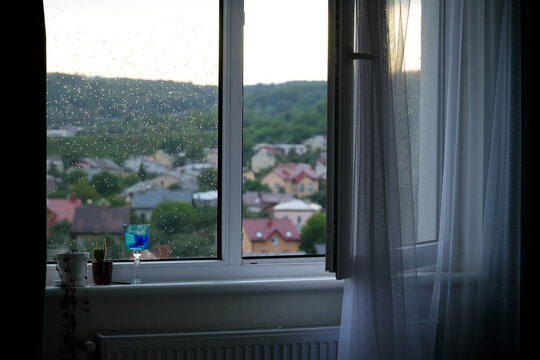 home dusk peaceful atmosphere of open window with cactus plant and glass on a sill in rainy time with water drops