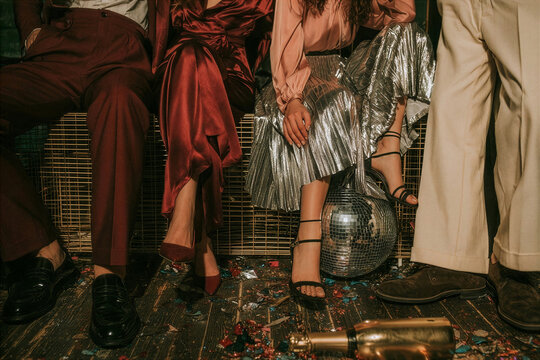 Legs and shoes of party guests standing near a disco ball on the floor