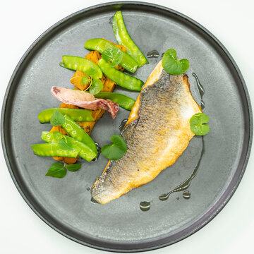 Pan-seared fish fillet with vegetables and herbs
