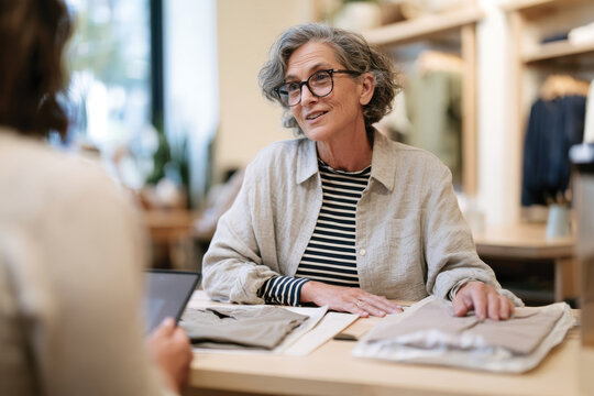 A senior woman discussing various clothing options in a store, exhibiting warmth and wisdom in her interactions, showcasing a welcoming shopping experience.