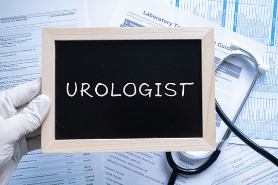 Urologist text on black chalkboard held by gloved hand with medical documents, urology healthcare concept