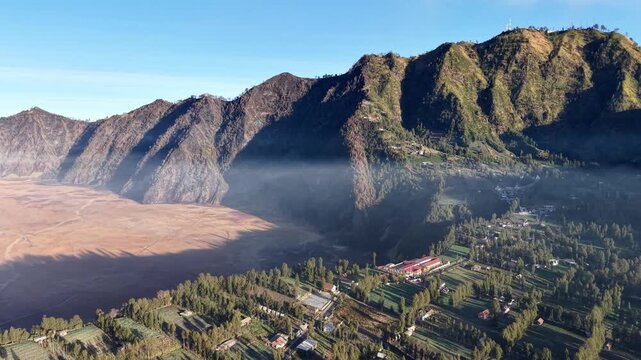 Misty mountain valley bathed in early morning light. Steam drifts softly from the crater floor at Bromo