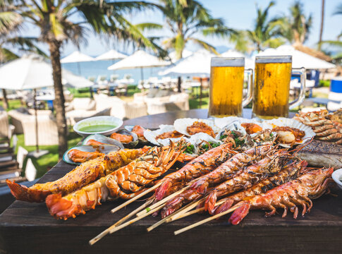 Grilled seafood platter with prawns and beer by the beach