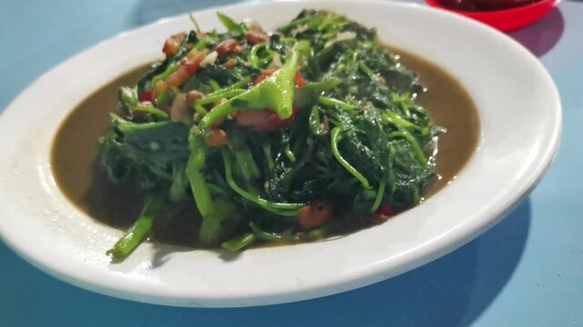 Stir-fried water spinach plecing kangkung on oval plate