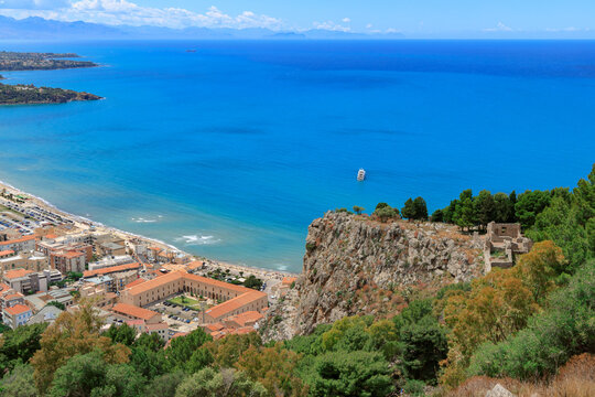 Aerial view of a coastal resort town with a historic building and rocky cliffs by the blue sea