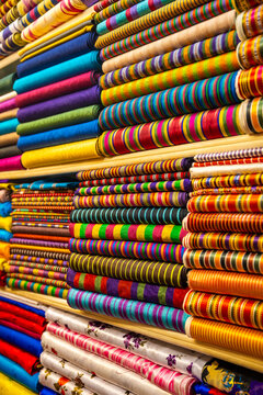 Colorful array of folded fabrics in various patterns and textures displayed on shelves in a textile shop