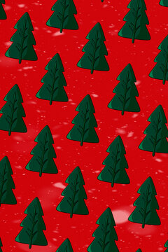Seamless pattern of dark green Christmas trees on red background with falling snow. Christmas wrapping paper, holiday wallpaper, social media posts, textile prints and winter seasonal designs.