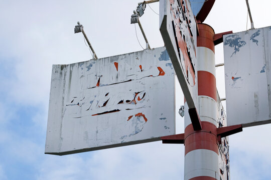 Faded and weathered billboard on a large metal pole