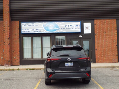 Ottawa, Ontario, Canada &ndash; July 19, 2026: A black Toyota SUV is parked outside a commercial building featuring a sign for "Reliable Services" at 5330 Canotek Rd Suite 37.