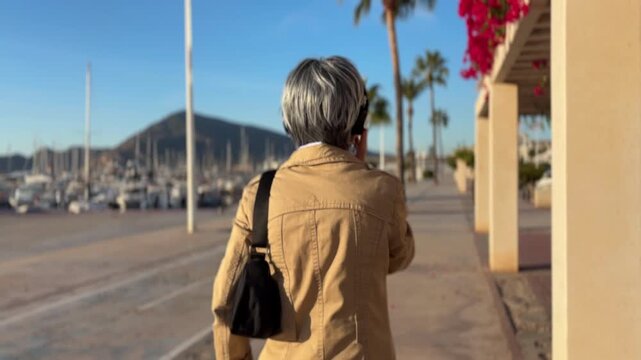 Mujer +50 paseando con auriculares junto a un carril bici