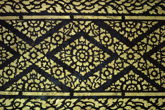 Traditional ornate gold and black Thai pattern fabric texture background close-up