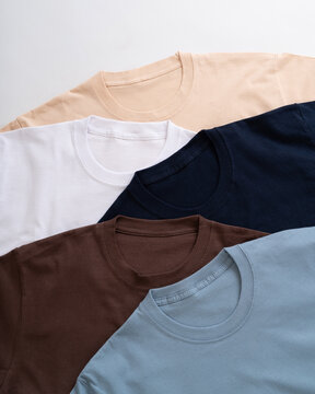 Stack of colorful cotton t-shirts in various neutral and earth tone shades arranged neatly