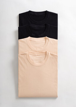 Stack of folded black and beige cotton t shirts arranged vertically on a white background
