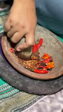 Traditional Process of Making Indonesian Sambal Terasi Chili Paste in a Stone Mortar