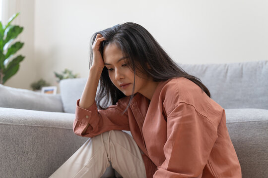 Stressed female feeling depressed and lonely on the sofa in the house.