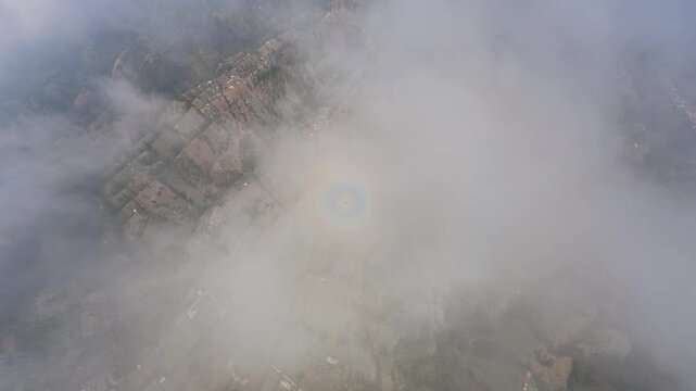 Drone fisheye aerial over foggy valley with circular halo above agricultural terraces.