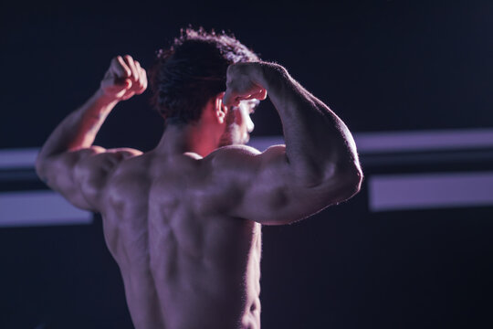 Rear View of Muscular Bodybuilder Flexing Back Muscles in GymShirtless Athletic Man Showing Strong Definition and Bicep FlexFitness Athlete Displaying Powerful Physique and Broad Shoulders