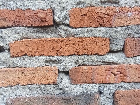 Texture of a red brick wall  with a layer of gray cement.