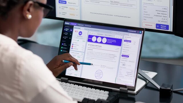 Notary Reviewing Documents On Laptop