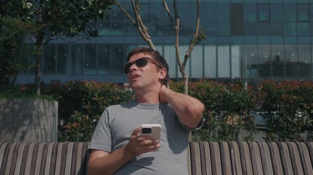 Text neck pain after prolonged smartphone use, man rubbing sore neck from poor head posture, excessive mobile screen use and sedentary digital habit.