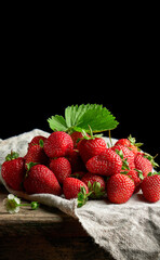 Ripe juicy strawberries with leaves on a linen napkin and wooden table © nndanko