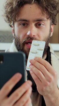 Vertical video. Man with running nose, caughing having video call with doctor while staying at home. Patient video conferencing with general practitioner on smartphone.