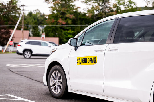 White minivan marked Student Driver sits in a parking lot, a driving school vehicle used for lessons. A learner driver concept covering teen driving, practice, and road safety, with no people present
