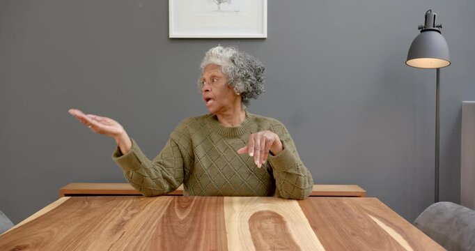 Close up of people talking to the camera, sitting at wooden table, elderly woman in home