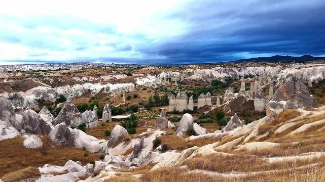 Heavy rain clouds loom over the towering fairy chimneys of Love Valley in Cappadocia Turkey. A dramatic, moody sunrise scene highlighting the rugged volcanic terrain of Anatolia