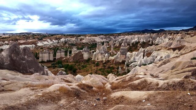 Moody overcast dawn sky casting dramatic shadows over the iconic tuff rock pillars of Love Valley in Cappadocia Turkey. Rugged geological formations under severe weather conditions
