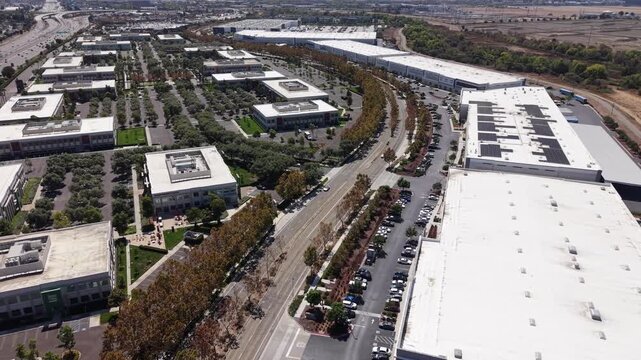 Drone pull out shot over a modern business park with corporate offices and a large distribution warehouse center in Milpitas, California, showcasing infrastructure and logistics