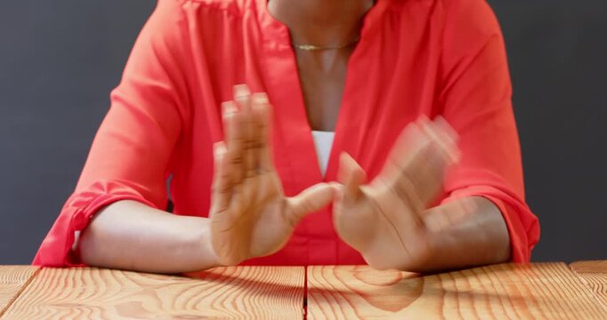 Close up of people talking to the camera, sitting at wooden table, woman in red blouse clasping hand