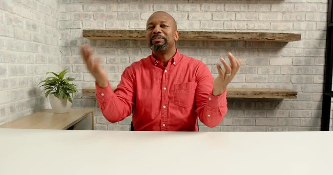 Close up of people talking to the camera, explaining, man in red shirt gesturing at desk