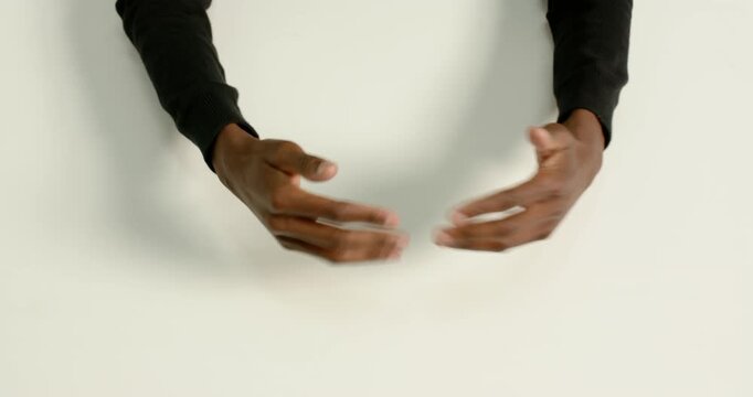 Close up of people talking to the camera, clenched fists on white surface