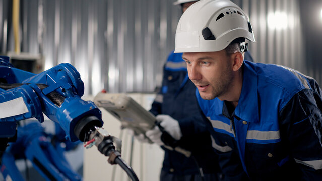 Robotics specialists team inspect welding torch on customized robotic arm in warehouse, safety, precision, reliability, before shipment.