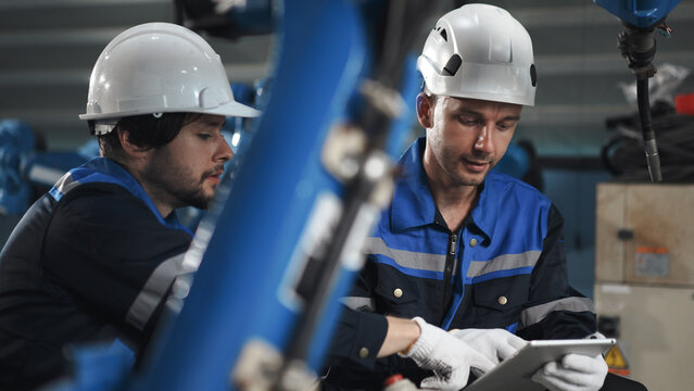 Robotics specialists team discuss for customized robot programming welding robotic arm at robot warehouse. solutions software, motion control, precision, reliability.