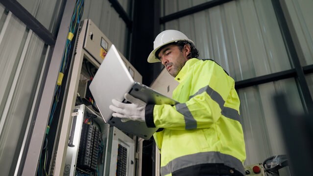 Preventive maintenance, Electrical engineer using laptop working electrical system inspection beside control panel in factory. diagnostics, troubleshooting, safety, preventive service.