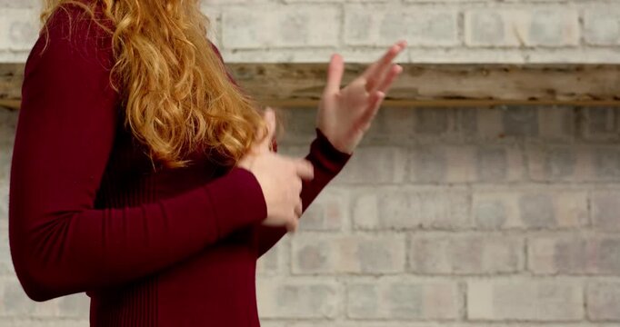 Close up of people talking to the camera, woman with red hair standing against brick wall, wearing m